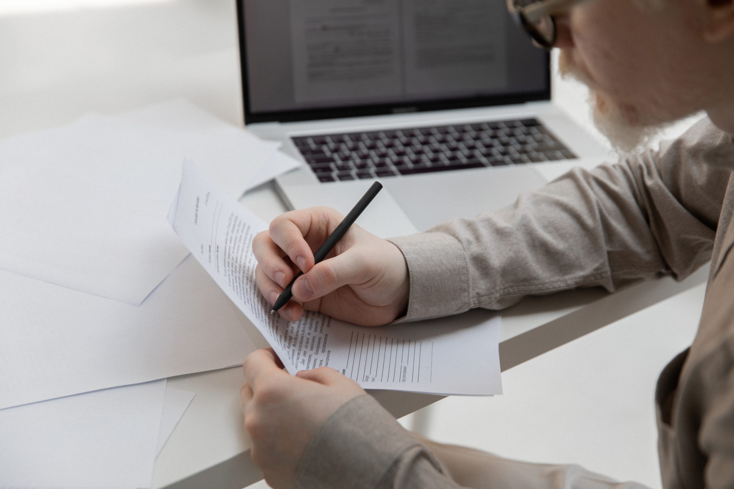 Crop office employee working with document near laptop